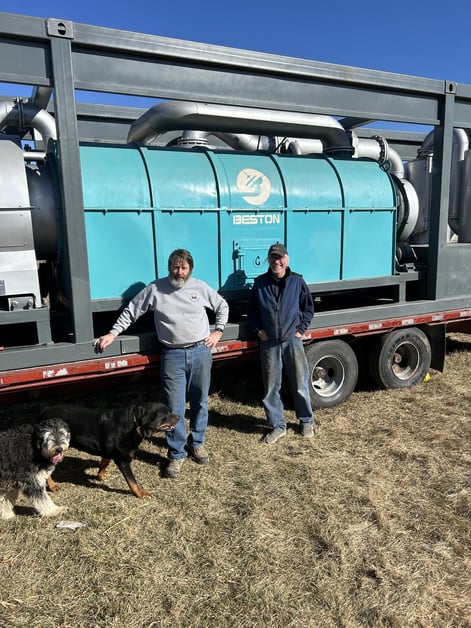 Two men and a dog standing in front of a truck